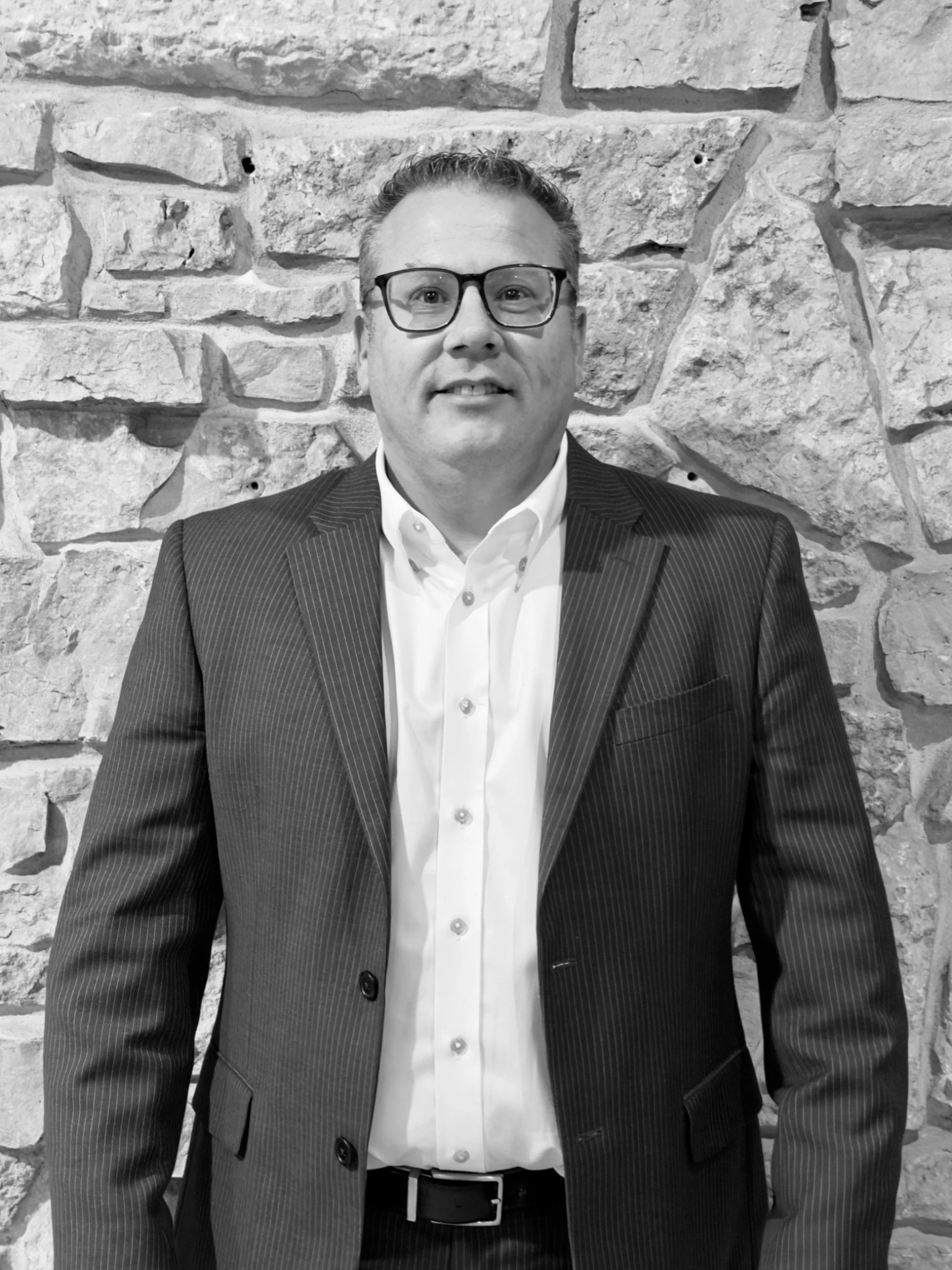 Darrin DeStasio in a pinstripe suit against a stone wall